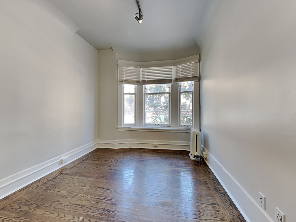 an empty living room with wood floors and a large window