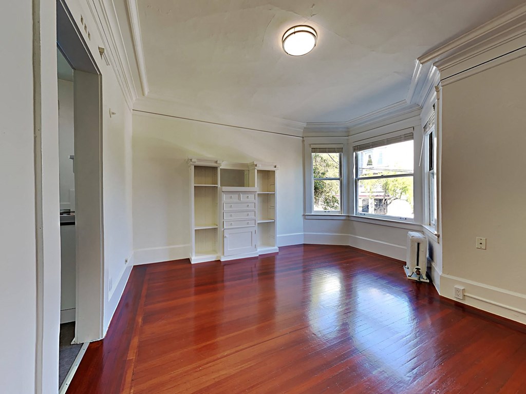 a living room with a large window and wooden floors
