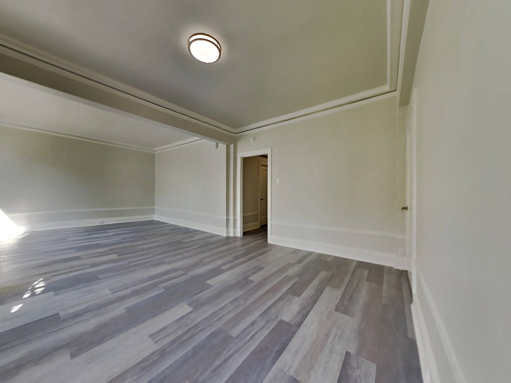 an empty living room with wood flooring and white walls