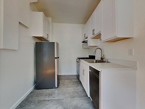 A kitchen with a black refrigerator and white cabinets.