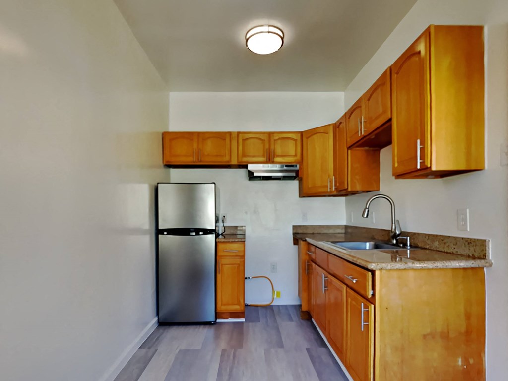 a kitchen with wooden cabinets and a stainless steel refrigerator