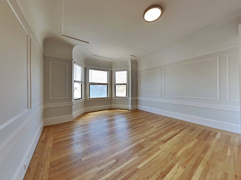 an empty living room with white walls and wood floors