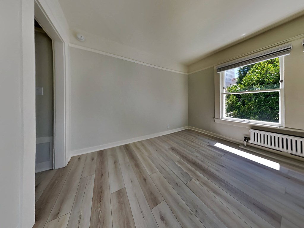 an empty living room with wooden floors and a window