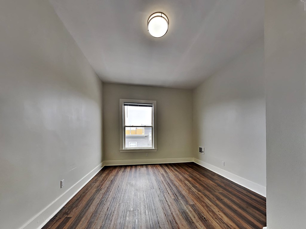 an empty living room with wood floors and a window