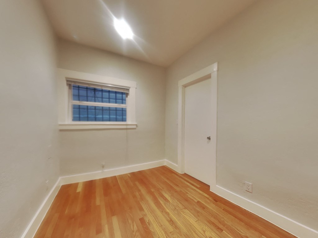 a bedroom with wood flooring and a window