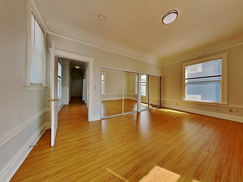 an empty living room with wood floors and a window
