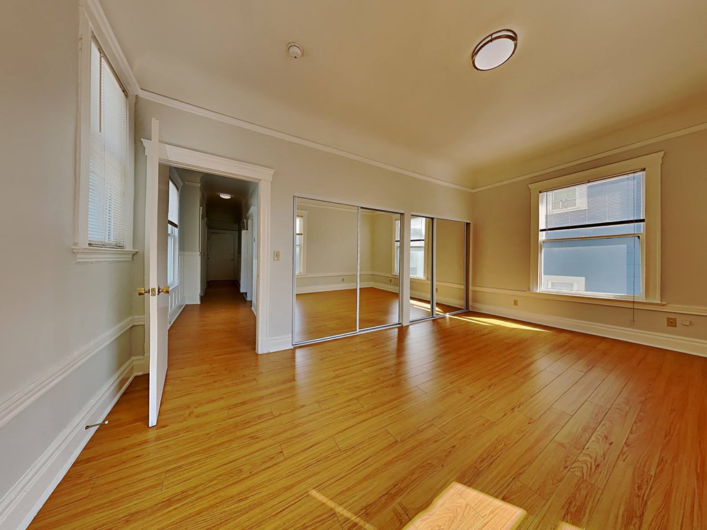 an empty living room with wood floors and a window