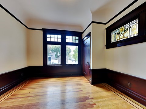A room with a wooden floor and a stained glass window.