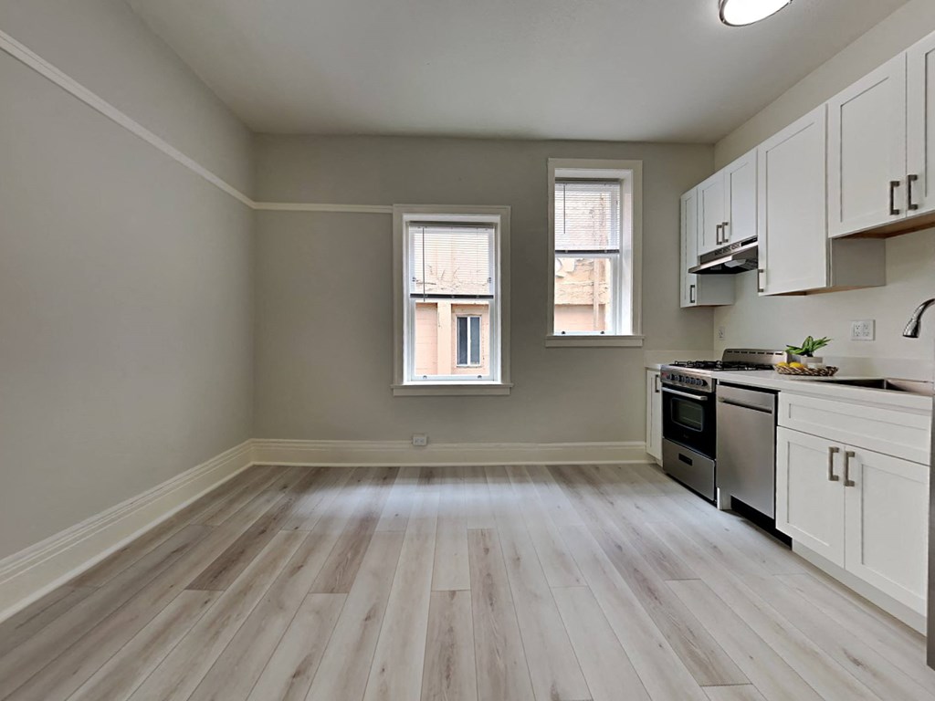 an empty kitchen with wood floors and white cabinets