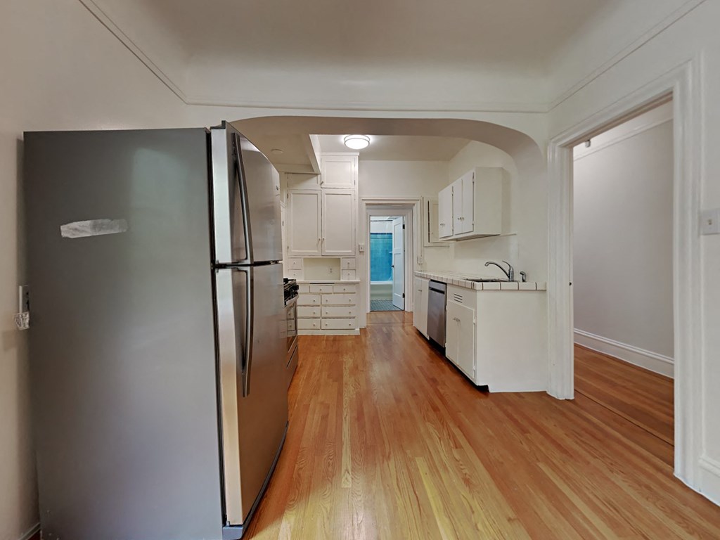 a kitchen with a stainless steel refrigerator and a wooden floor