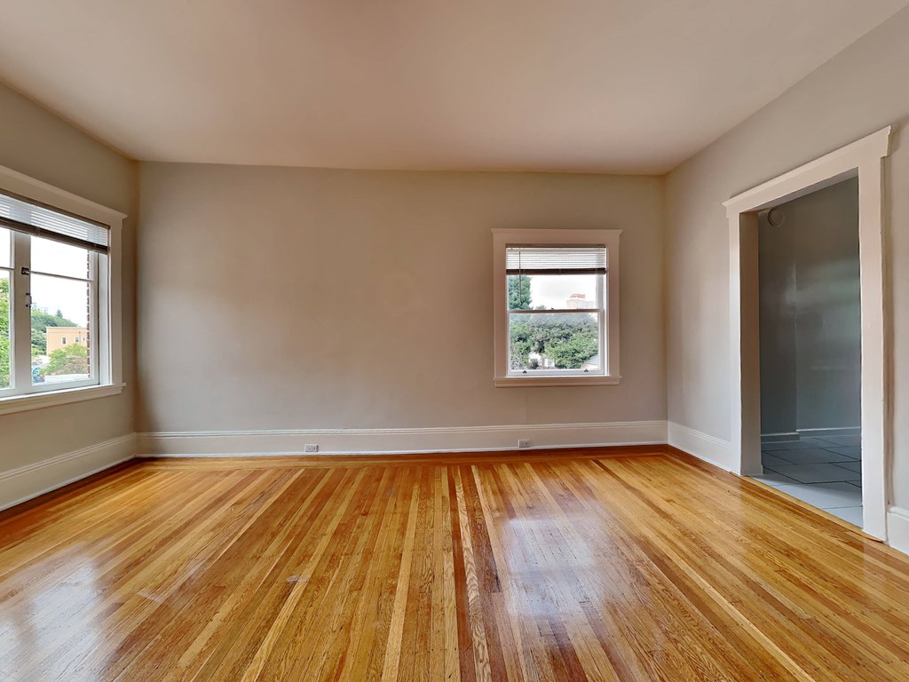 an empty living room with wood floors and a window