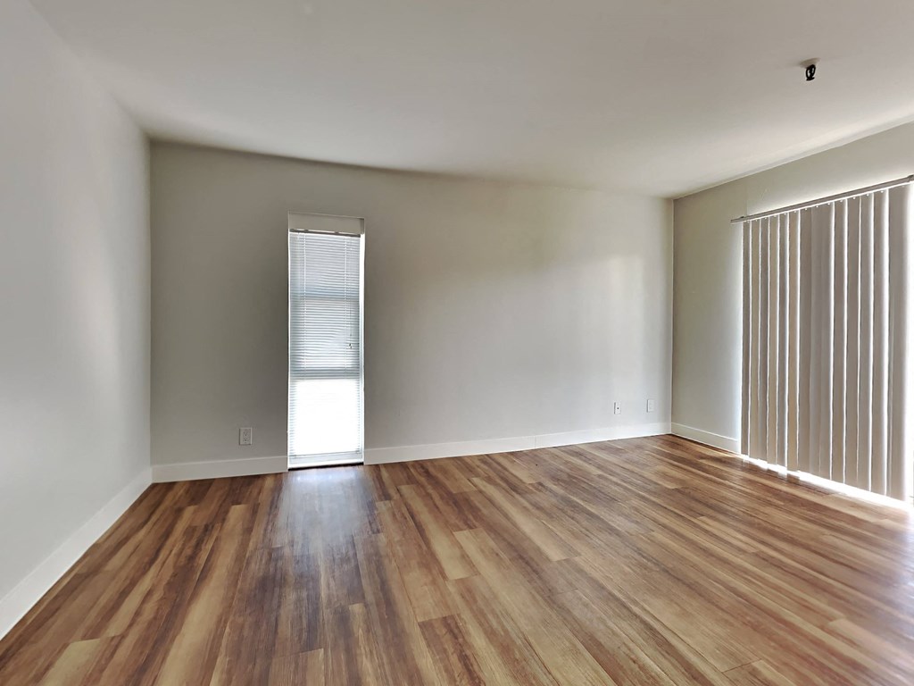 an empty living room with wood floors and a window