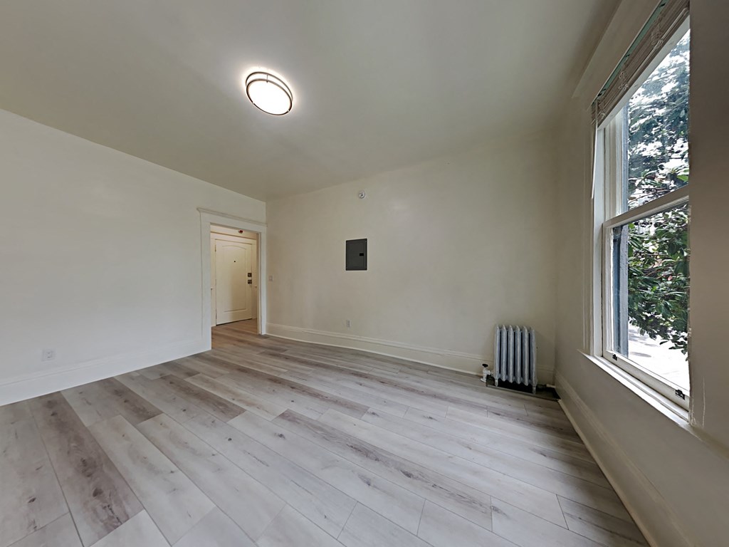 a living room with wood floors and white walls and a large window