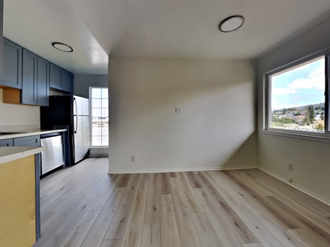 an empty living room and kitchen with wood floors and a large window