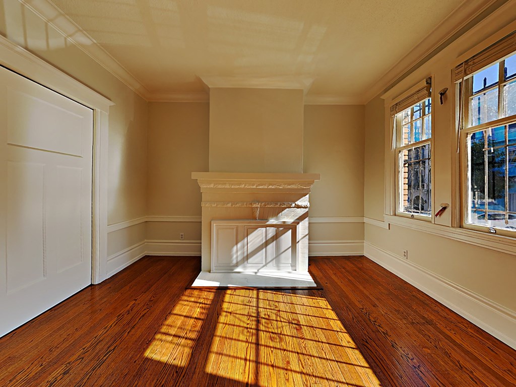 an empty living room with a fireplace and wooden floors