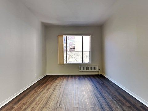 an empty room with wooden floors and a window
