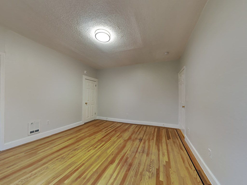 a spacious living room with wood flooring and white walls