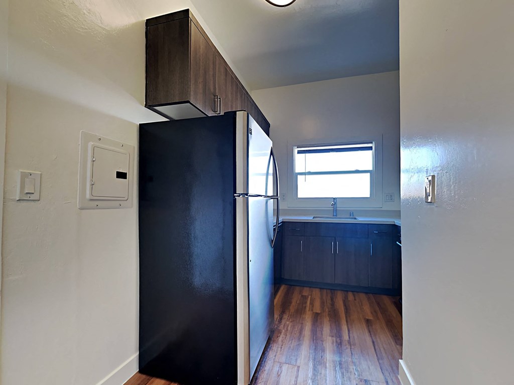 an empty kitchen with a refrigerator and a window