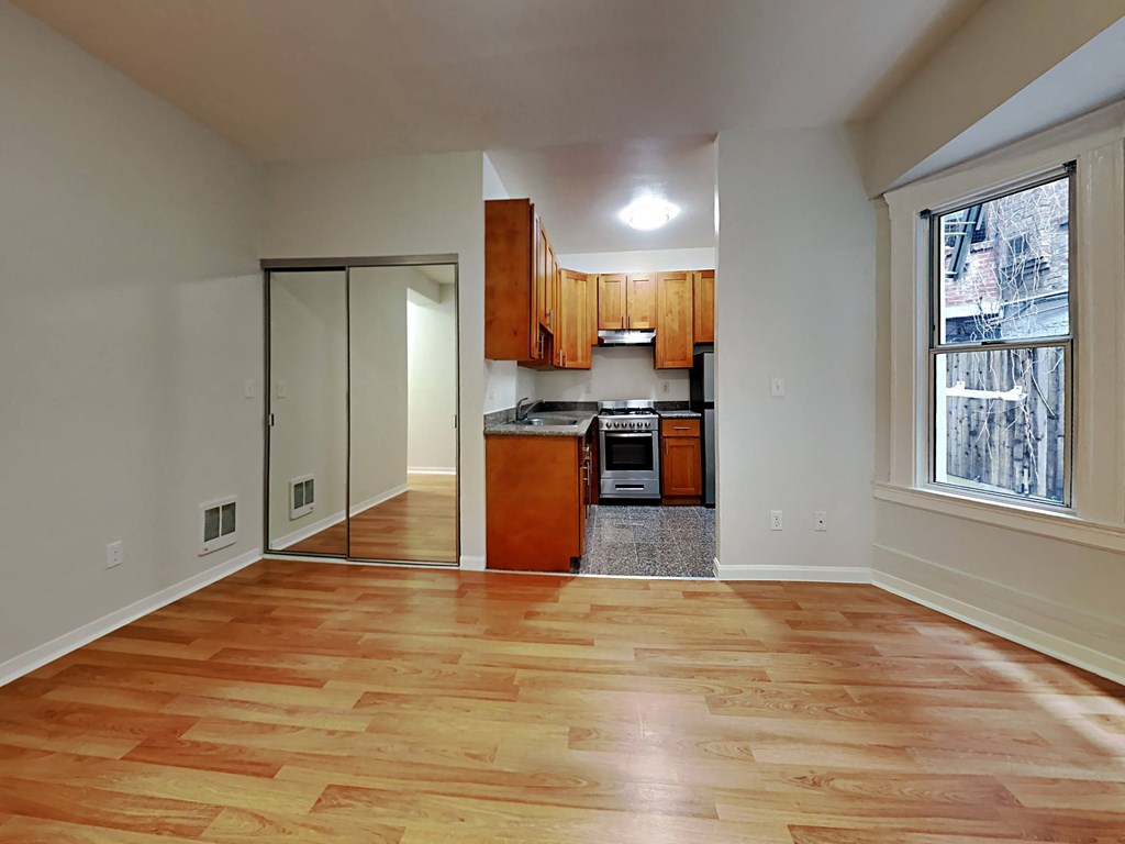 an empty living room with a kitchen and a large window