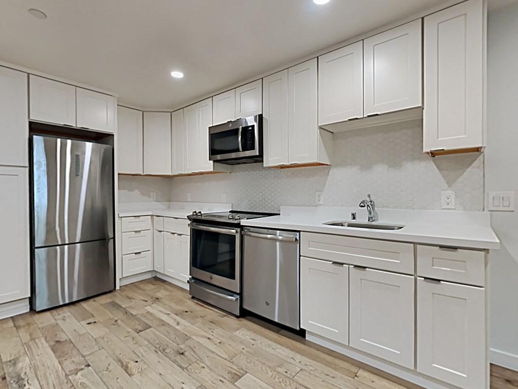 an empty kitchen with white cabinets and stainless steel appliances