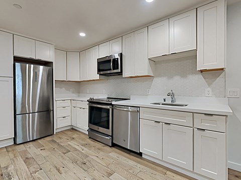 an empty kitchen with white cabinets and stainless steel appliances