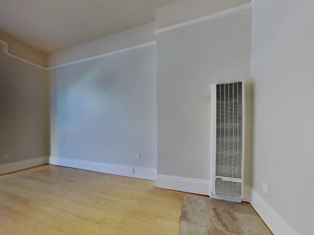a living room with white walls and a wood floor and a radiator