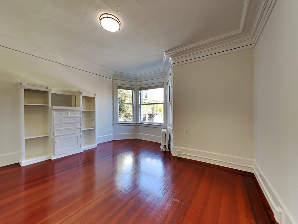 a living room with hardwood floors and a large window and white closets