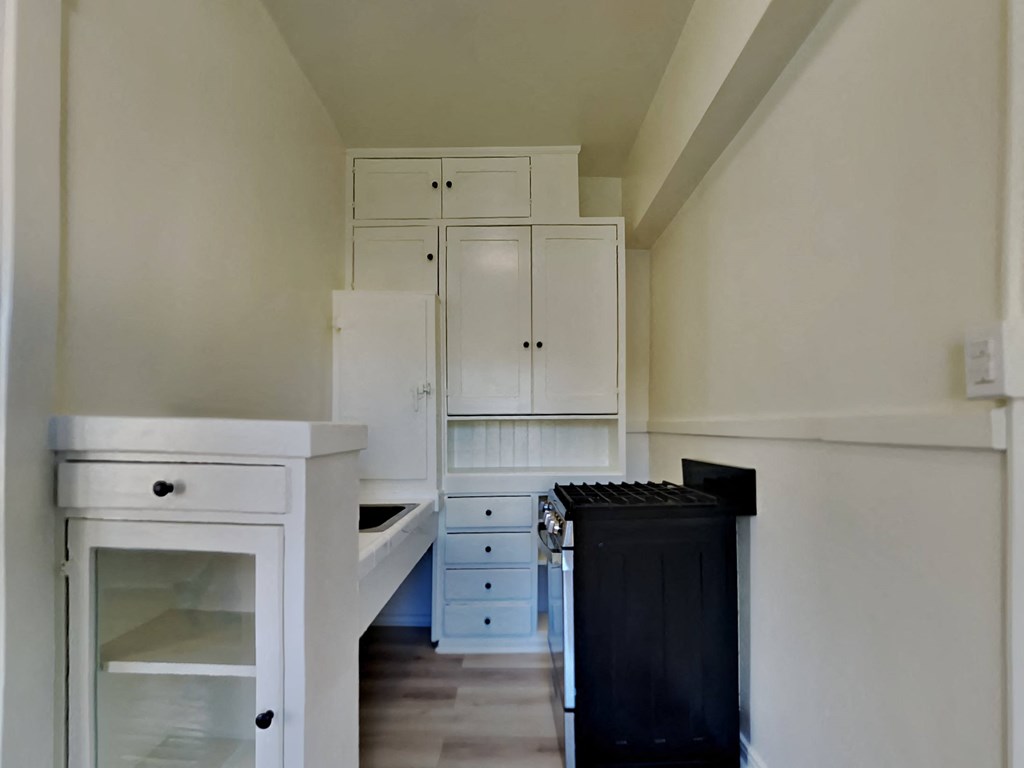a kitchen with white cabinets and a black stove