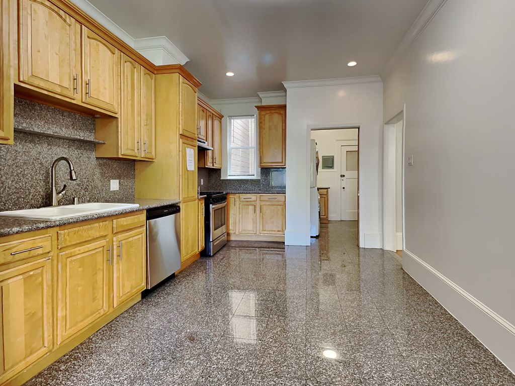 a large kitchen with wooden cabinets and granite floors