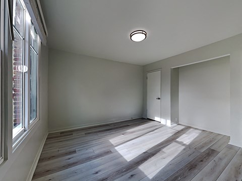 an empty room with wood flooring and a window