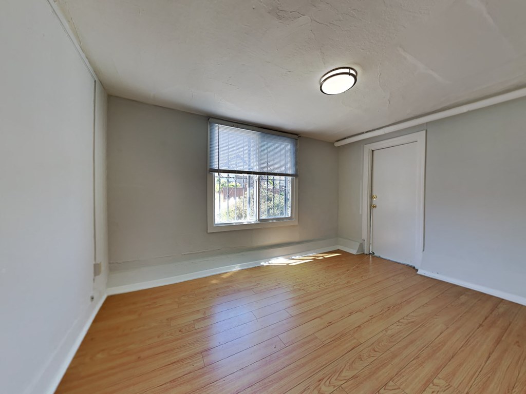 an empty living room with wood floors and a window