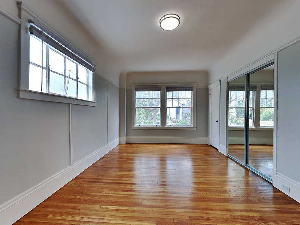 an empty living room with wood floors and a window