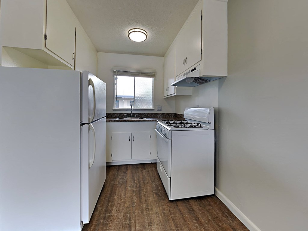 an empty kitchen with white appliances and white cabinets