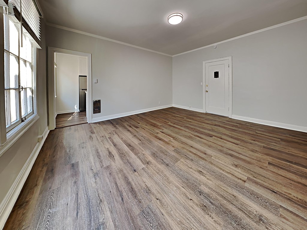 an empty living room with wood floors and white walls