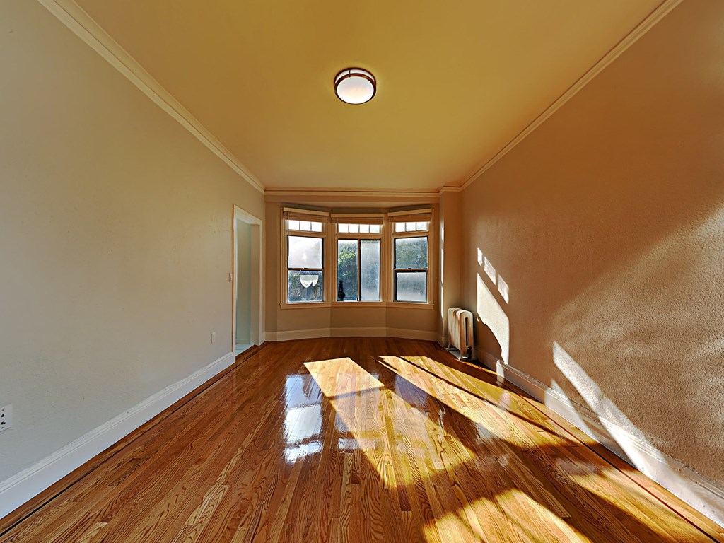 an empty living room with wood floors and a window