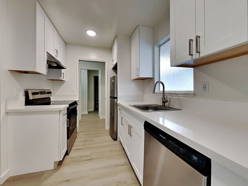 a kitchen with white cabinets and a black dishwasher and a sink