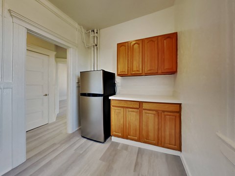 a small kitchen with a refrigerator and wooden cabinets