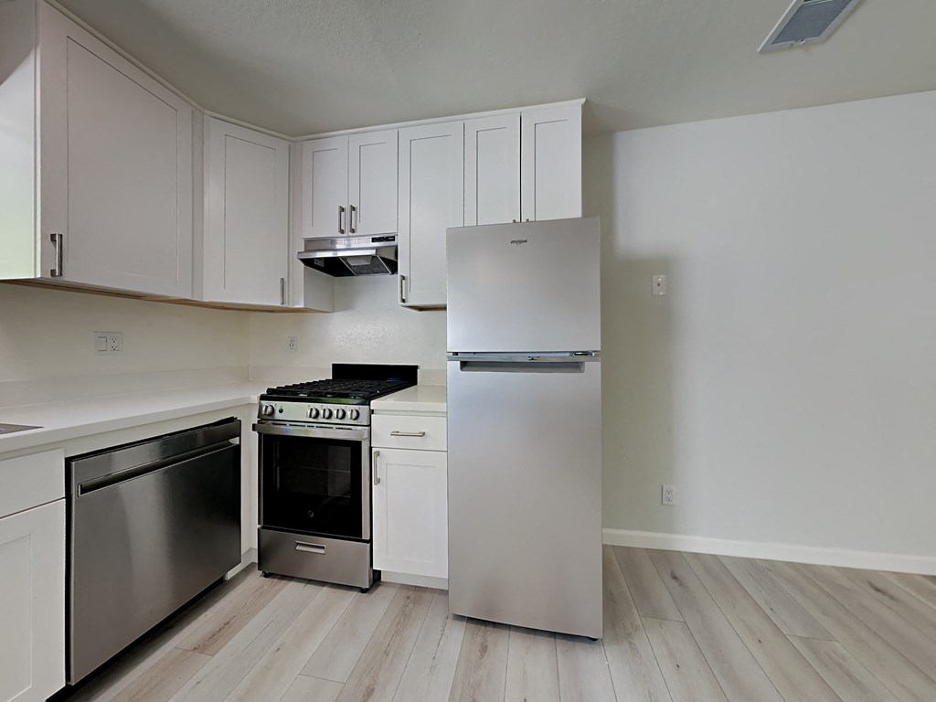 an empty kitchen with stainless steel appliances and white cabinets