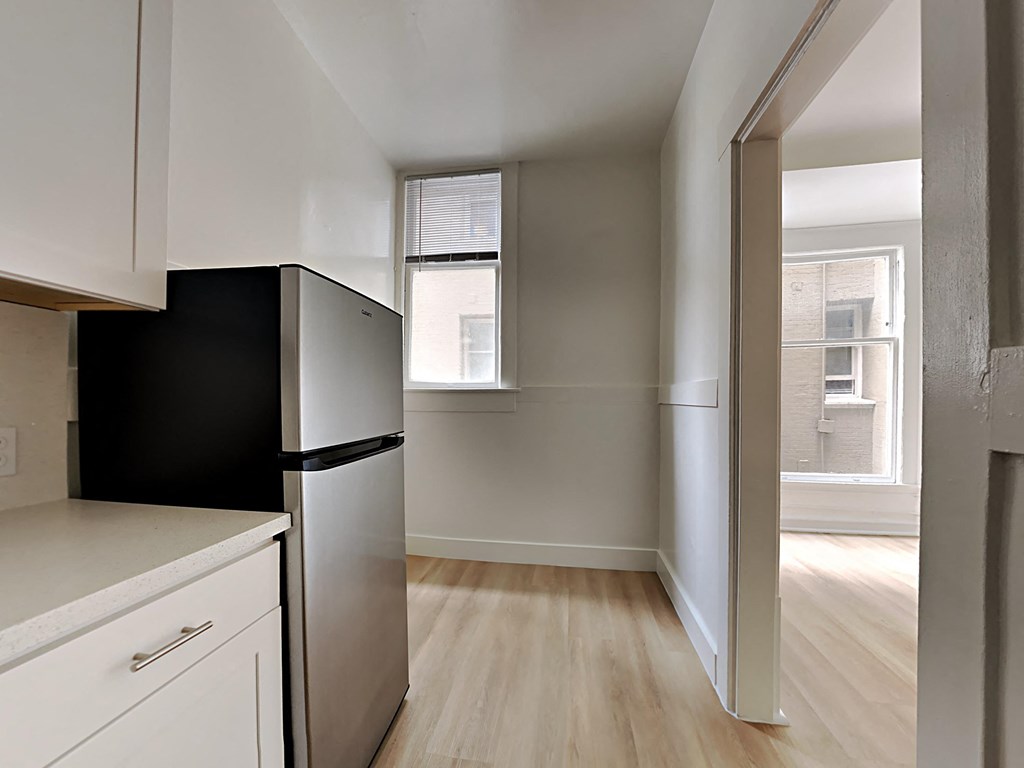an empty kitchen with a refrigerator and a window