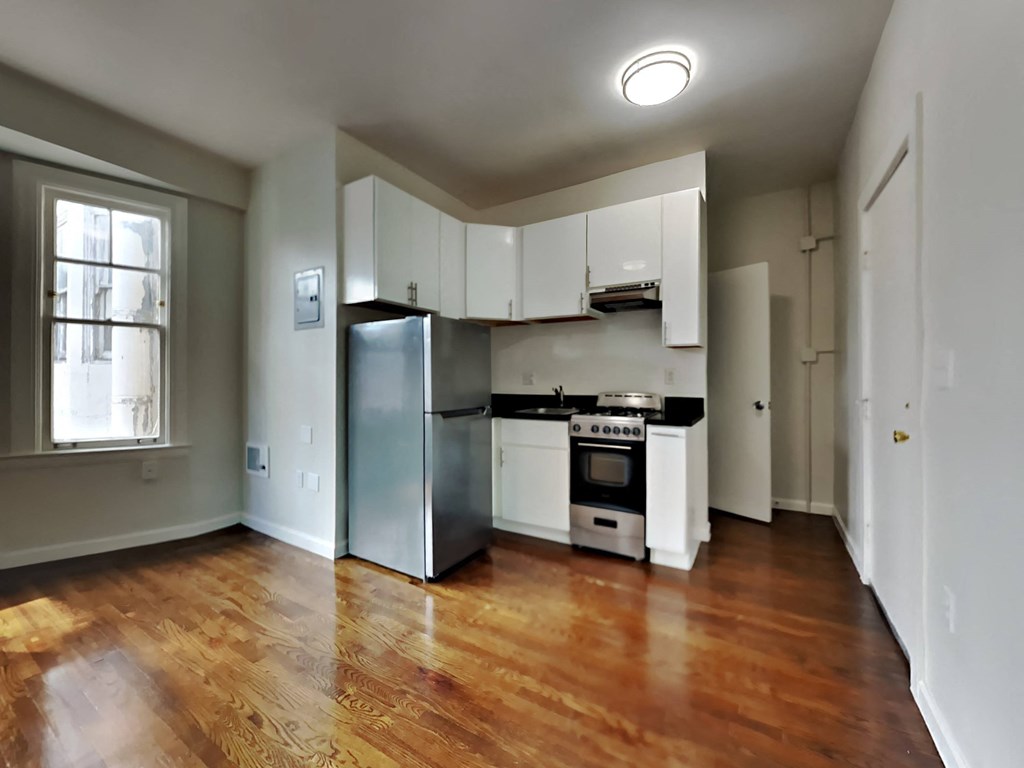 an empty kitchen with white cabinets and a stainless steel refrigerator