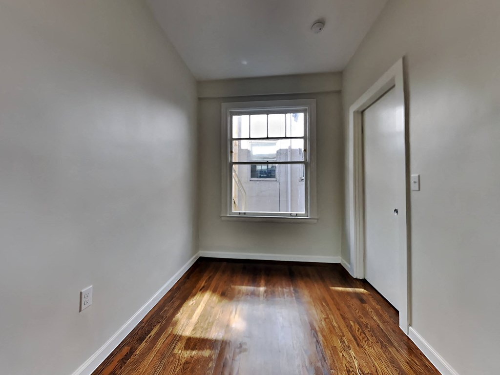 room with wood flooring and window in the corner