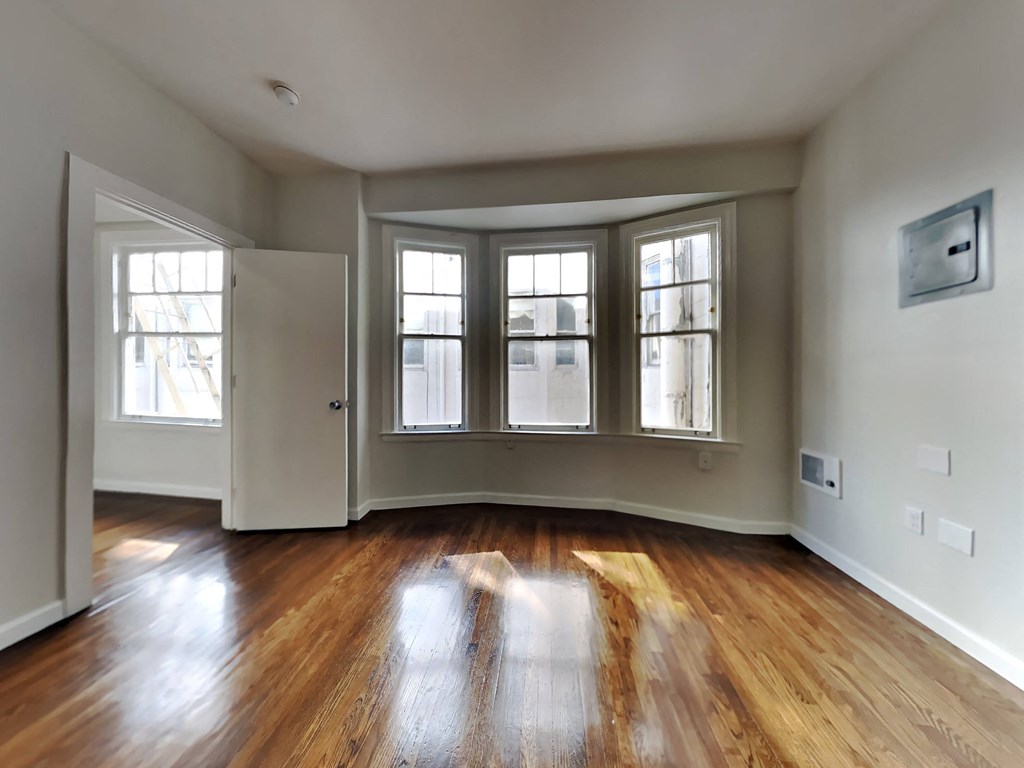 an empty living room with wood floors and windows