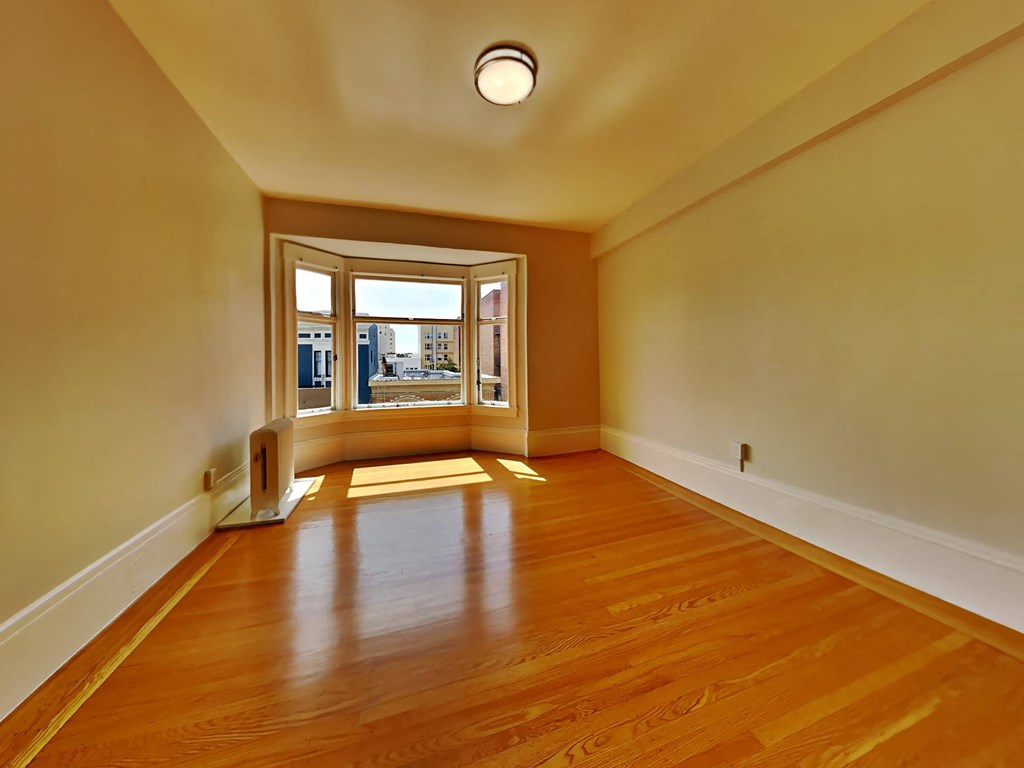 a empty living room with a large window and wooden floors