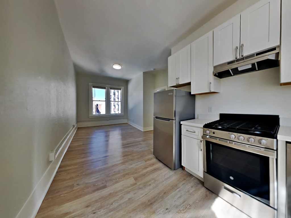 an empty kitchen with stainless steel appliances and white cabinets