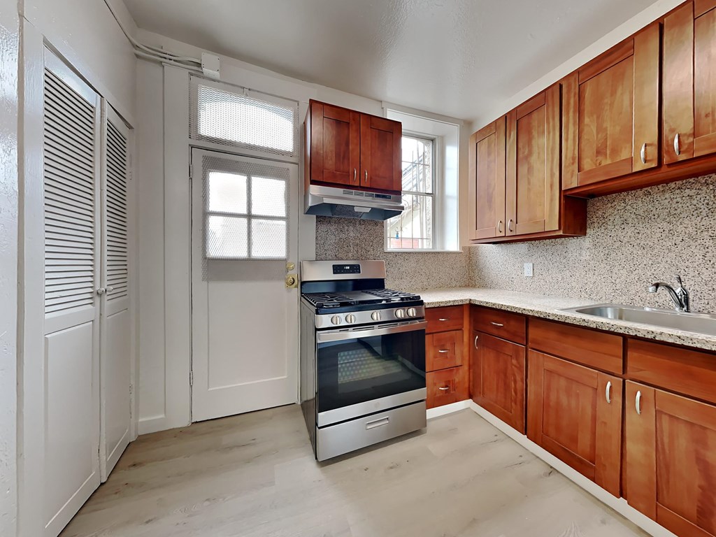 a kitchen with wooden cabinets and an oven and a sink