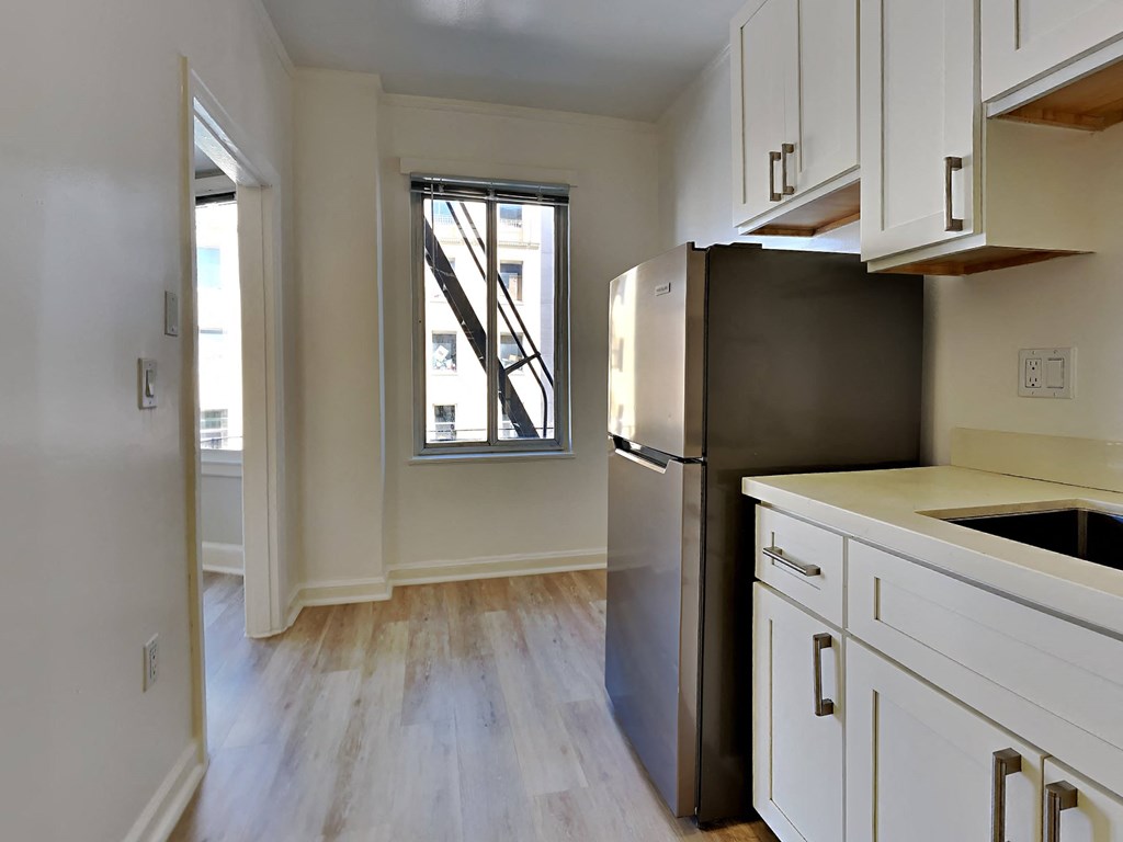 an empty kitchen with a refrigerator and a window