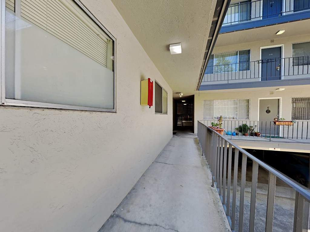 a long hallway with a railing and a building with a balcony