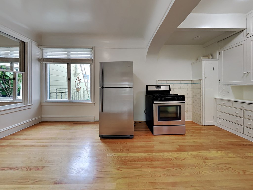 an empty kitchen with stainless steel appliances and white cabinets
