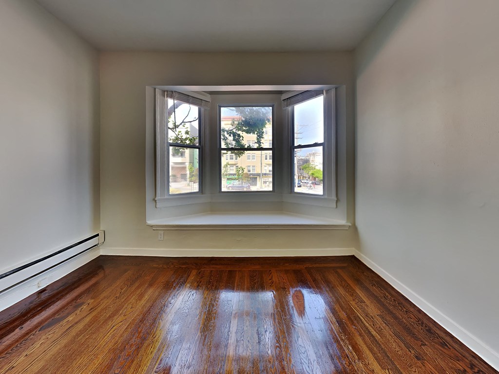an empty room with a window and wooden floors