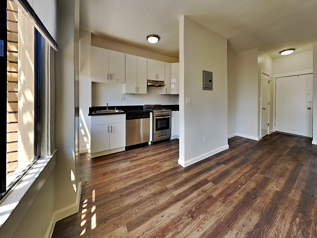 a renovated kitchen with white cabinets and a wood floor